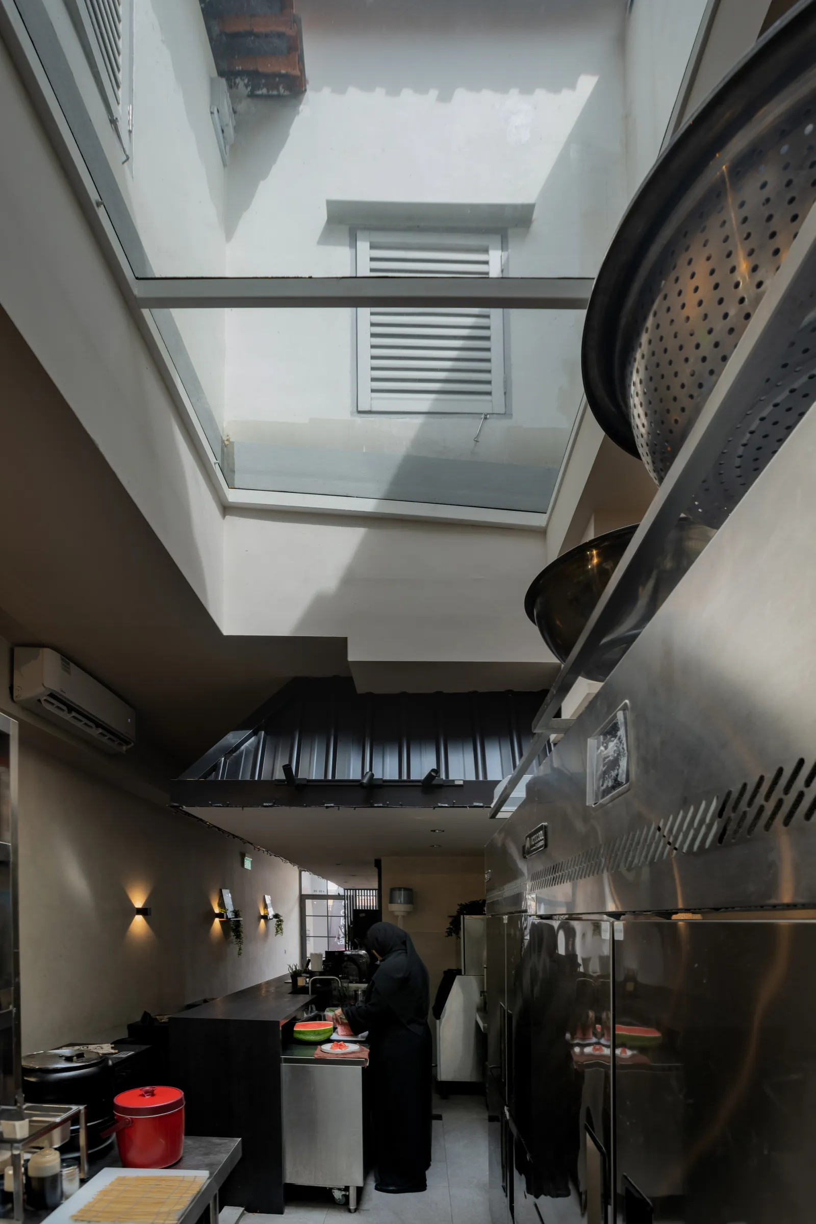 Hanok Shophouse: open kitchen under the existing skylight, beside the roofline