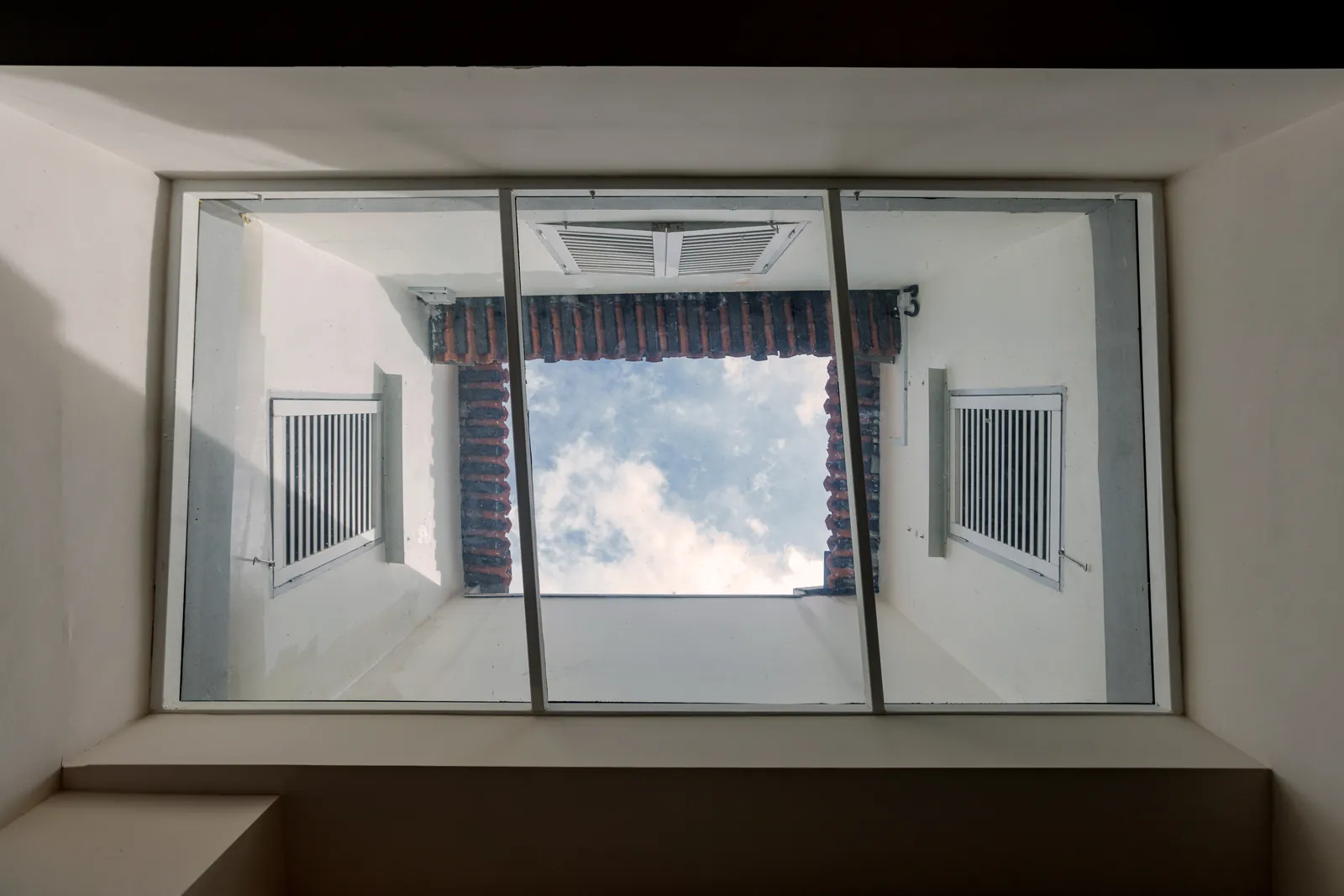 Hanok Shophouse: looking up through the existing skylight to the shophouse's air well and the sky