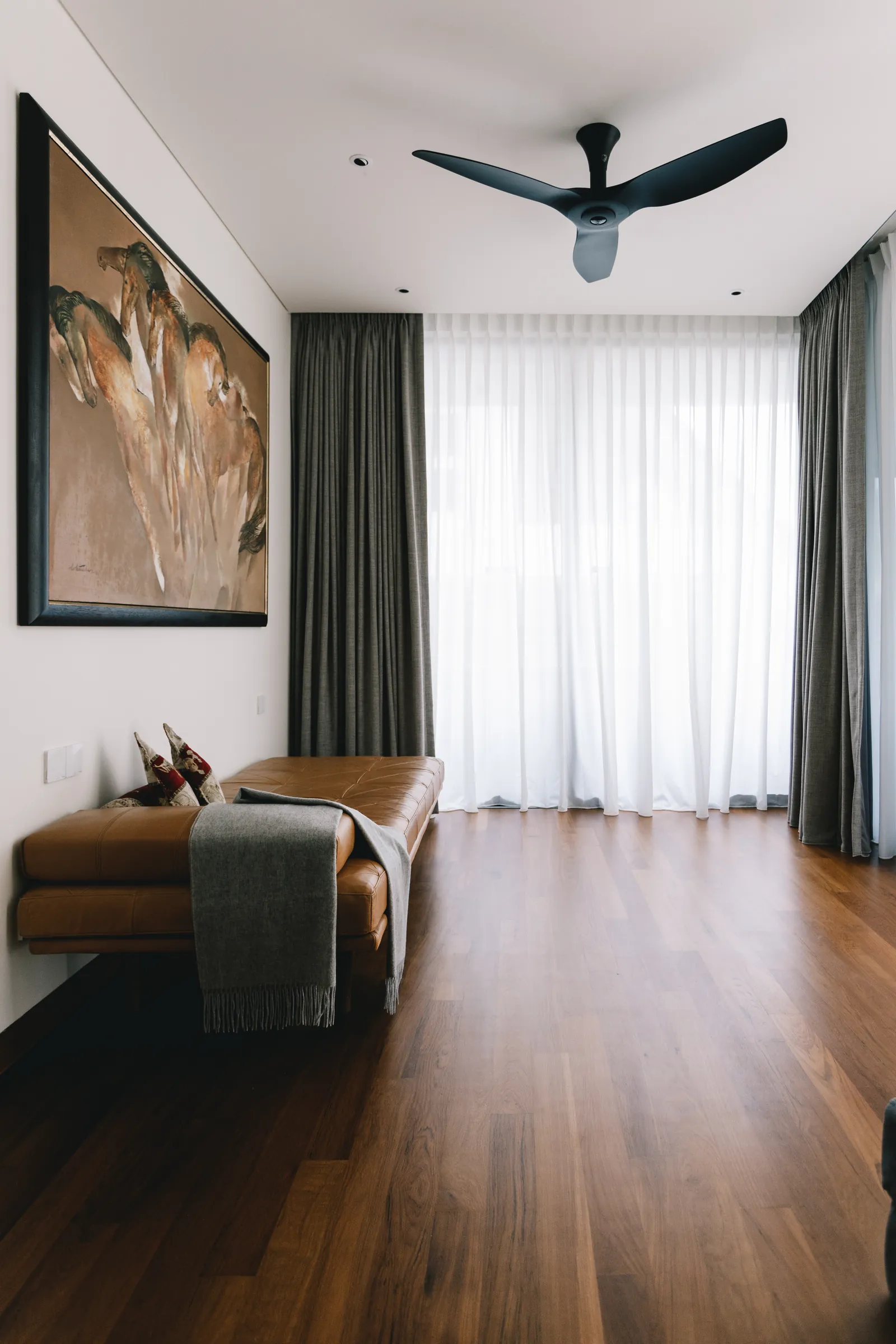 House of the Collector: bedroom with a leather bench, a large painting and a ceiling fan