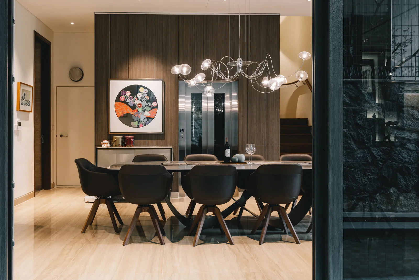 House of the Collector: dining room with a branching glass chandelier and a round painting on a timber wall