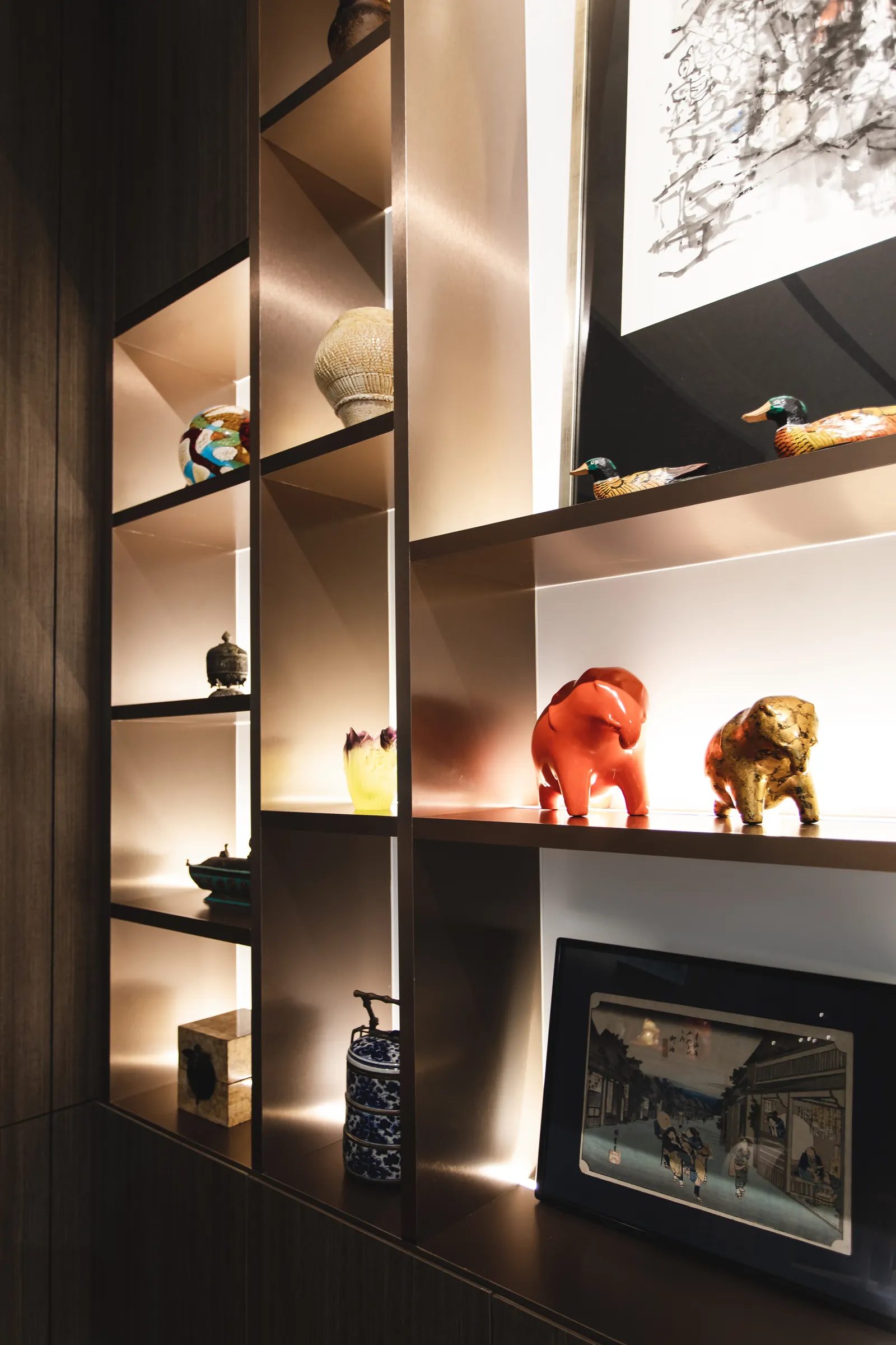 House of the Collector: lit display shelves with ceramics, figurines and a framed print