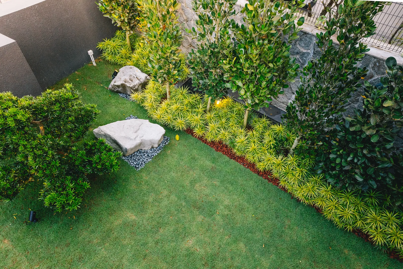 House of the Collector: lawn with boulders, young trees and bands of yellow-green planting, seen from above