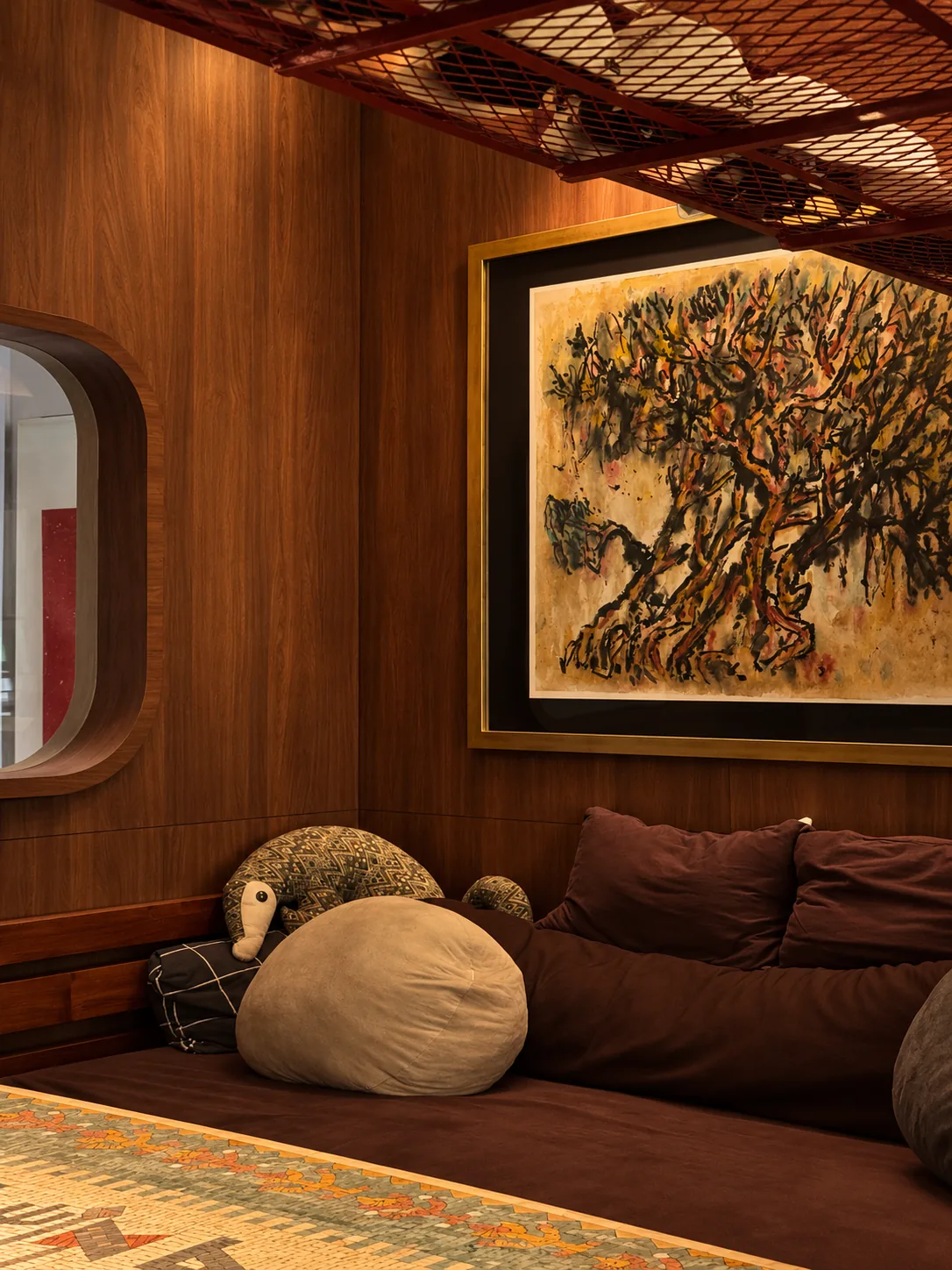 Library for the Arborist: a low sofa with cushions beneath the tree painting and the red steel rack