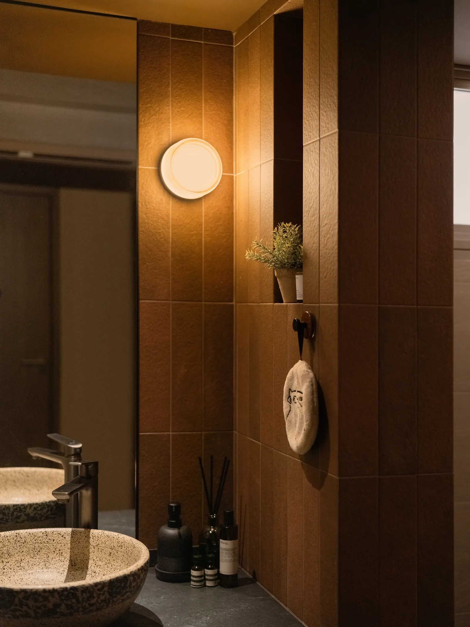 Mid Century Sanctuary: bathroom with terrazzo vessel basins, a round wall light and warm brown tiles