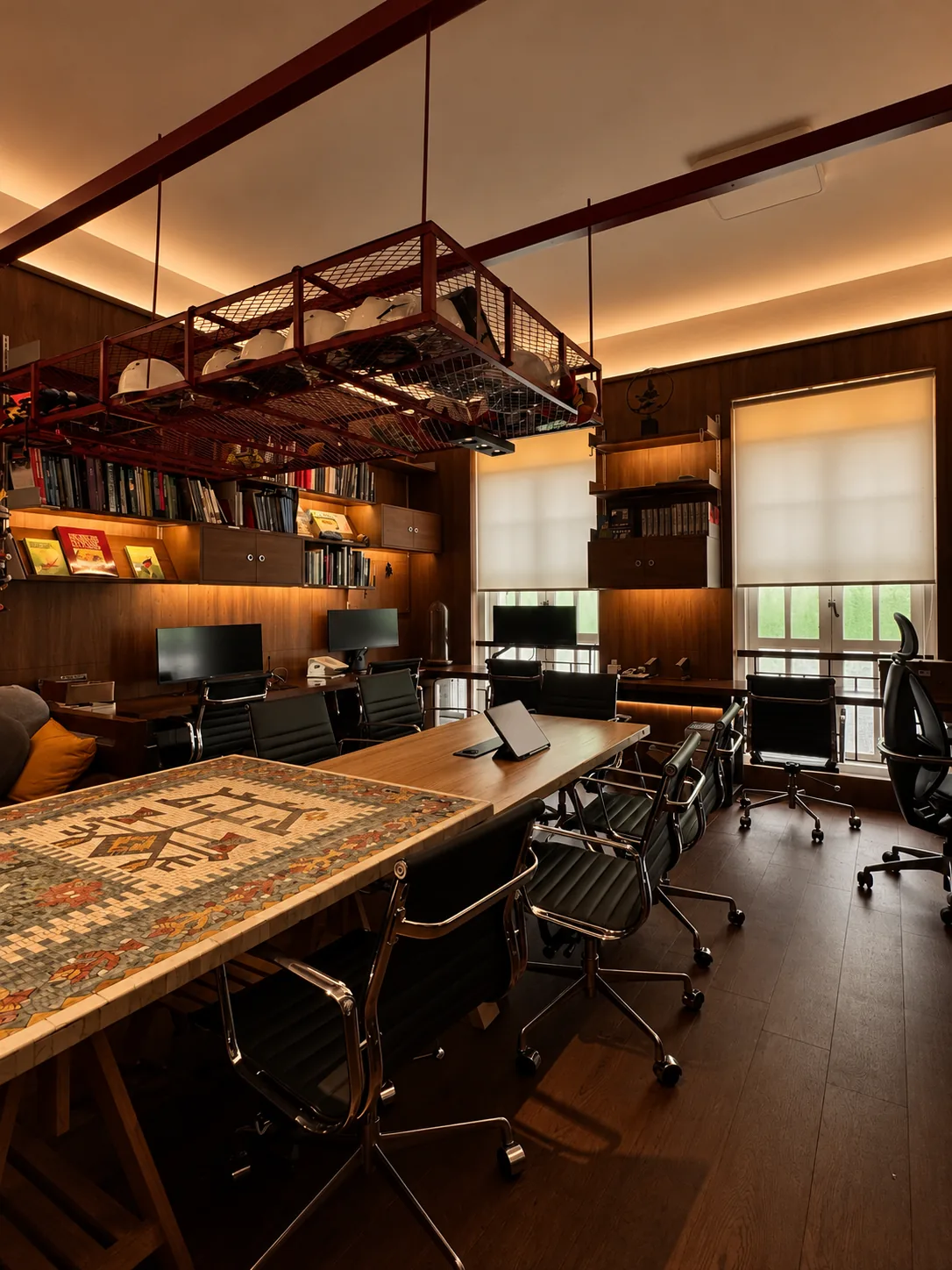 Library for the Arborist: the workroom, with a long mosaic-topped table under a red steel rack, bookshelves and desks by the windows