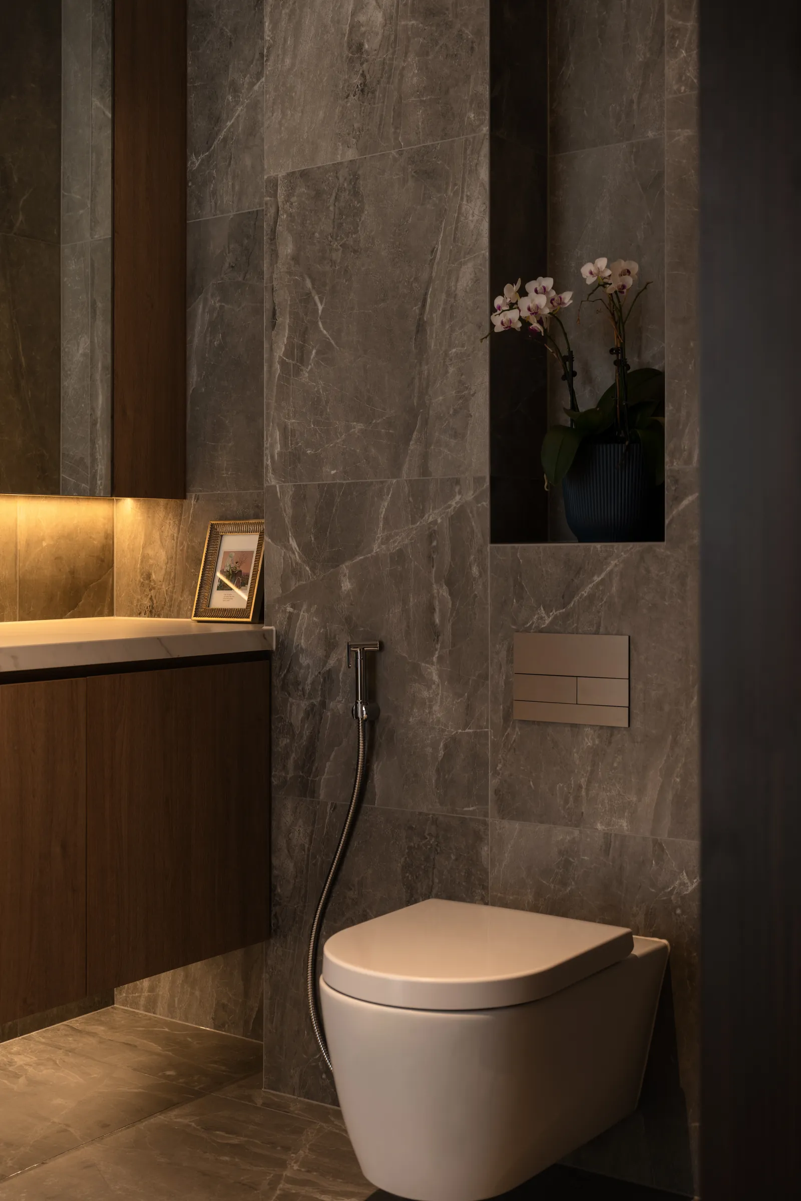 The Art of Retreat: bathroom in grey stone with an orchid in a lit niche