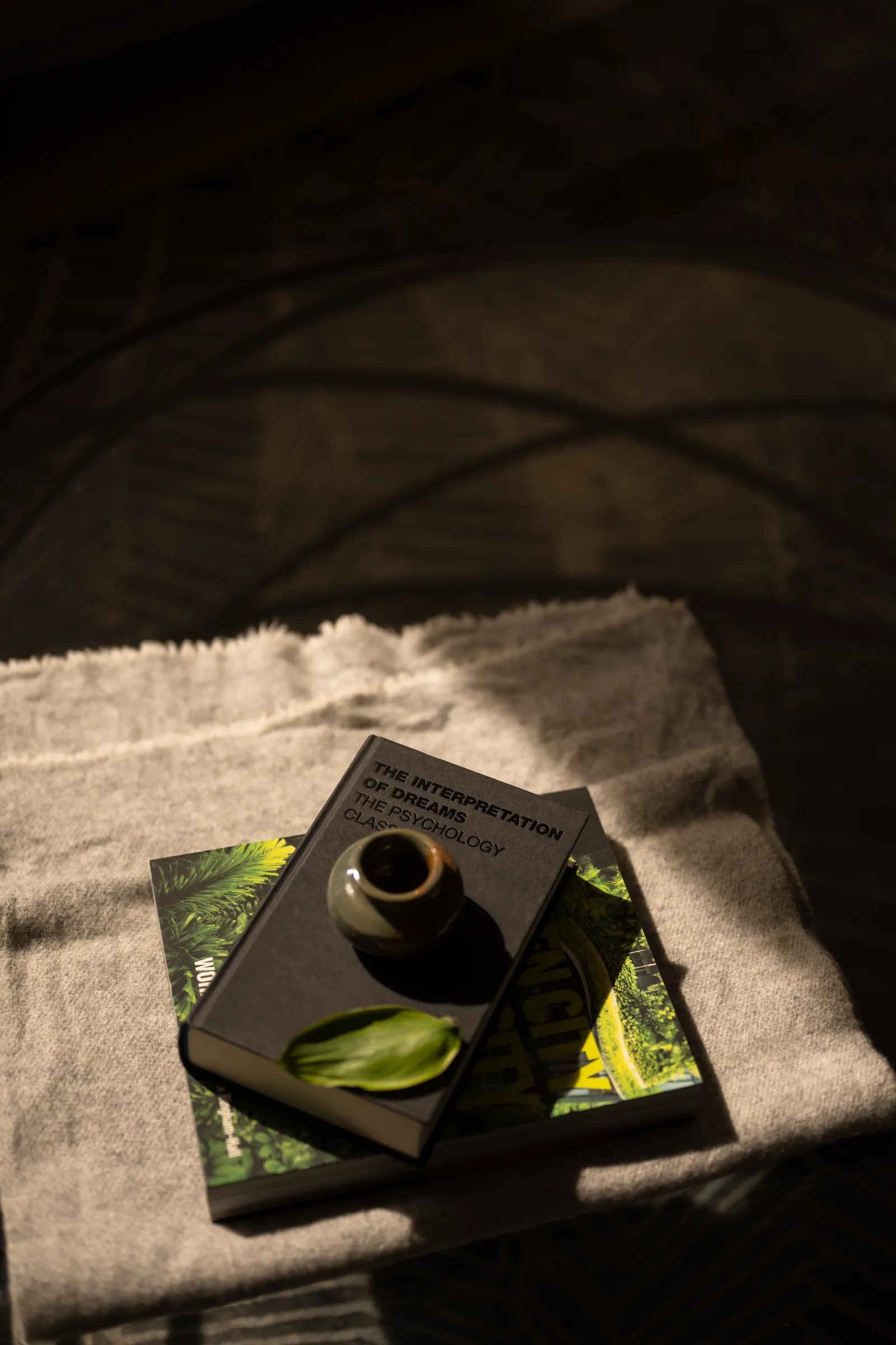 The Art of Retreat: a book and a small pot on a linen throw, in a patch of late light