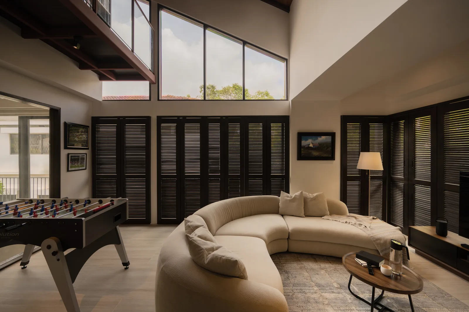 The Art of Retreat: lounge with a curved sofa and a foosball table under high windows