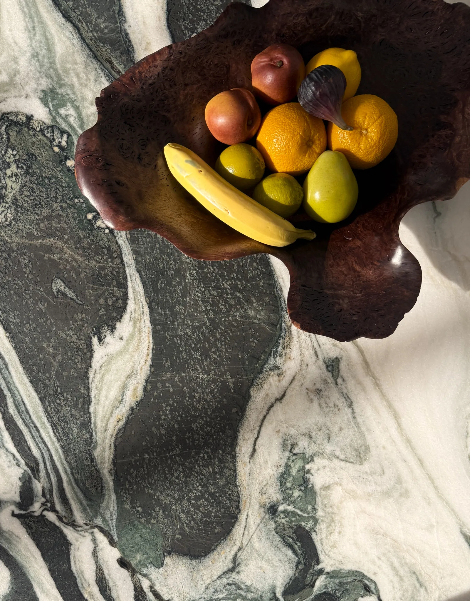 The Garden Within: fruit in a carved wooden bowl on green and white banded marble