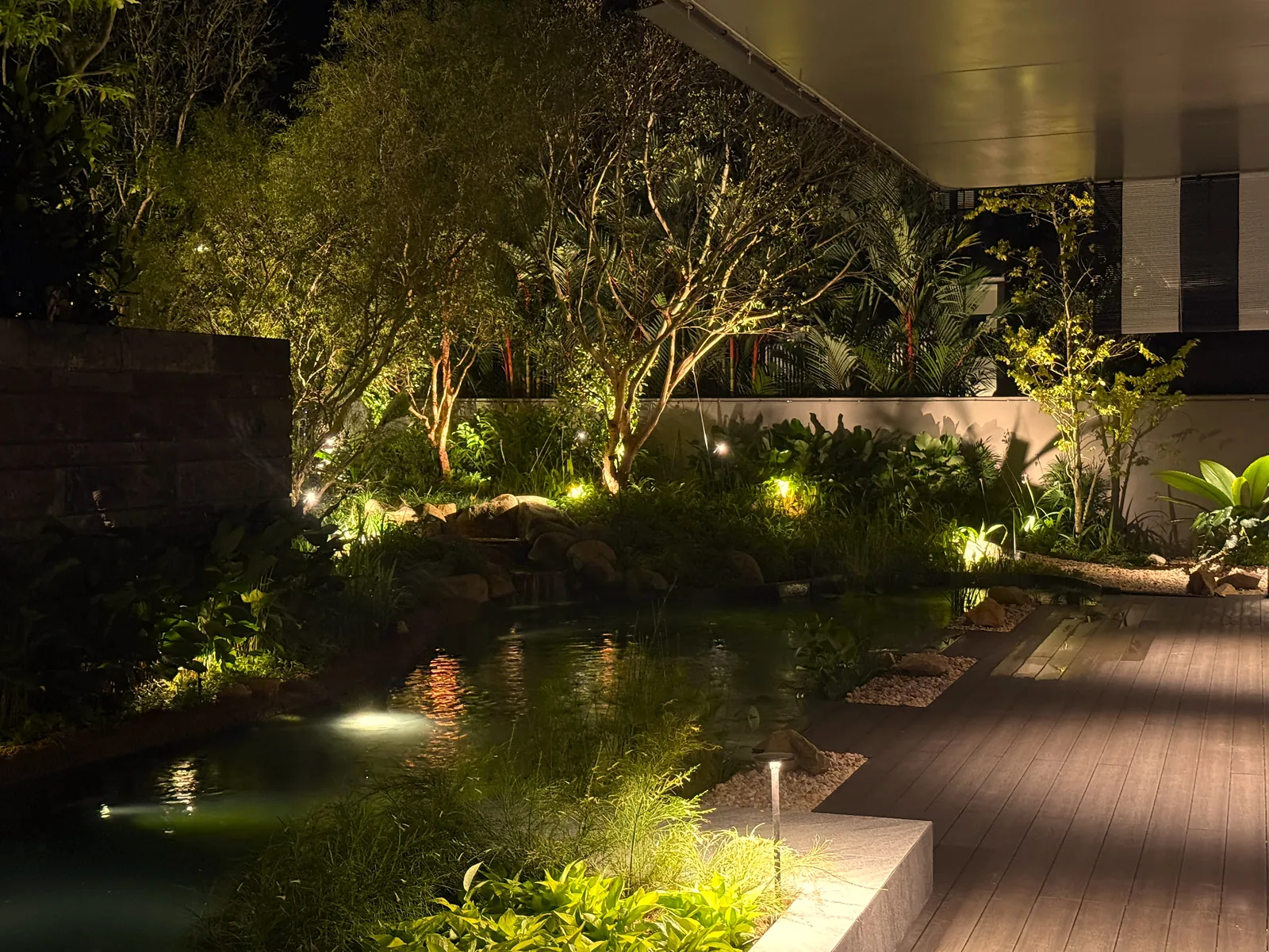 The Garden Within: the koi pond at night, lit beside the timber deck under the eaves