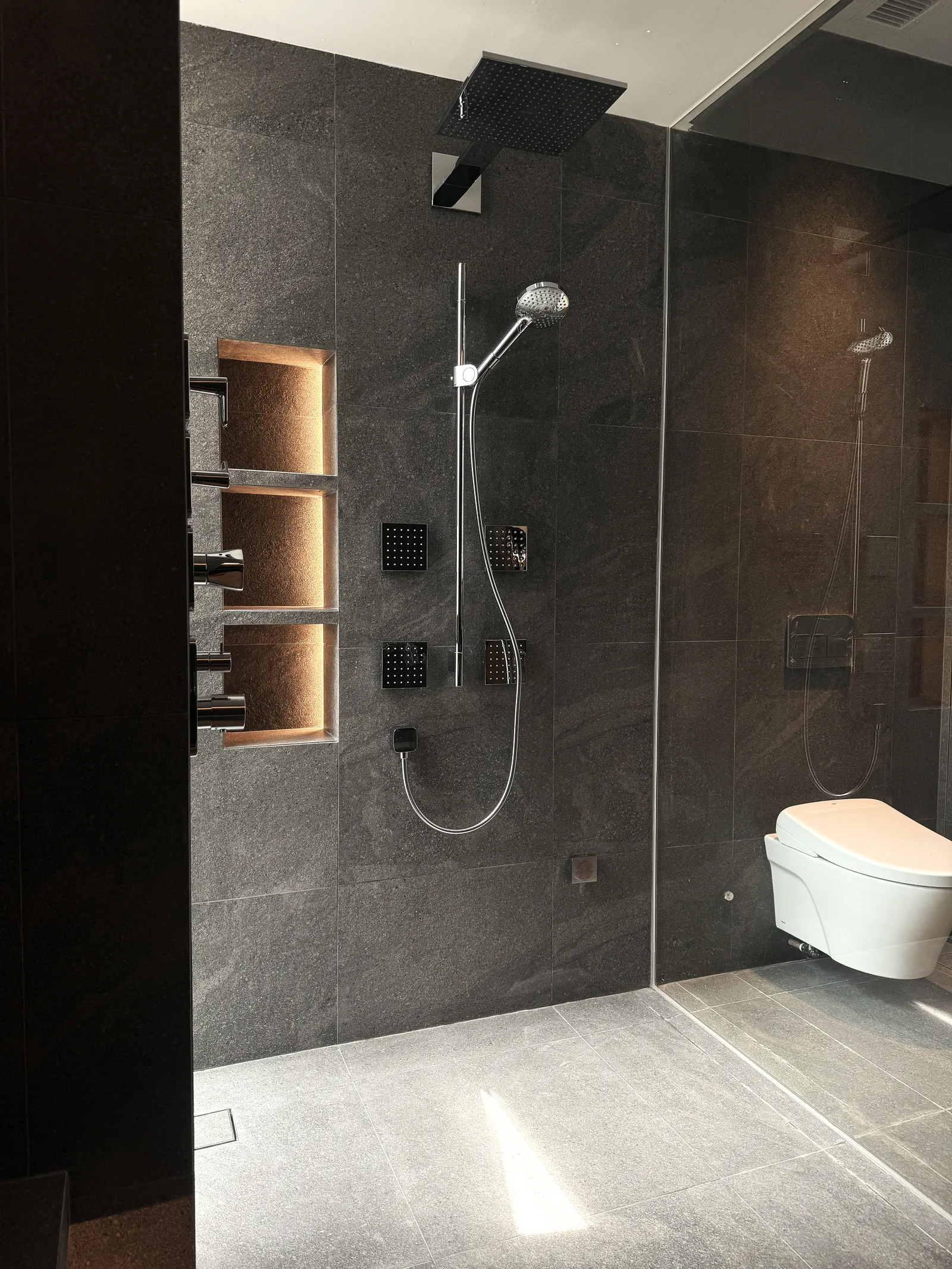 The Garden Within: walk-in shower in dark grey stone with lit wall niches