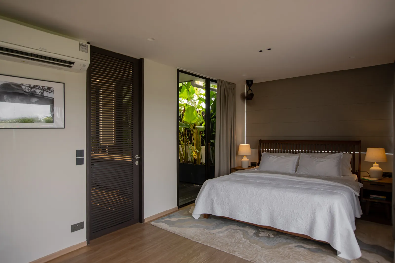 Villa in the Sky: bedroom with a timber bed frame and a glass door to a planted courtyard