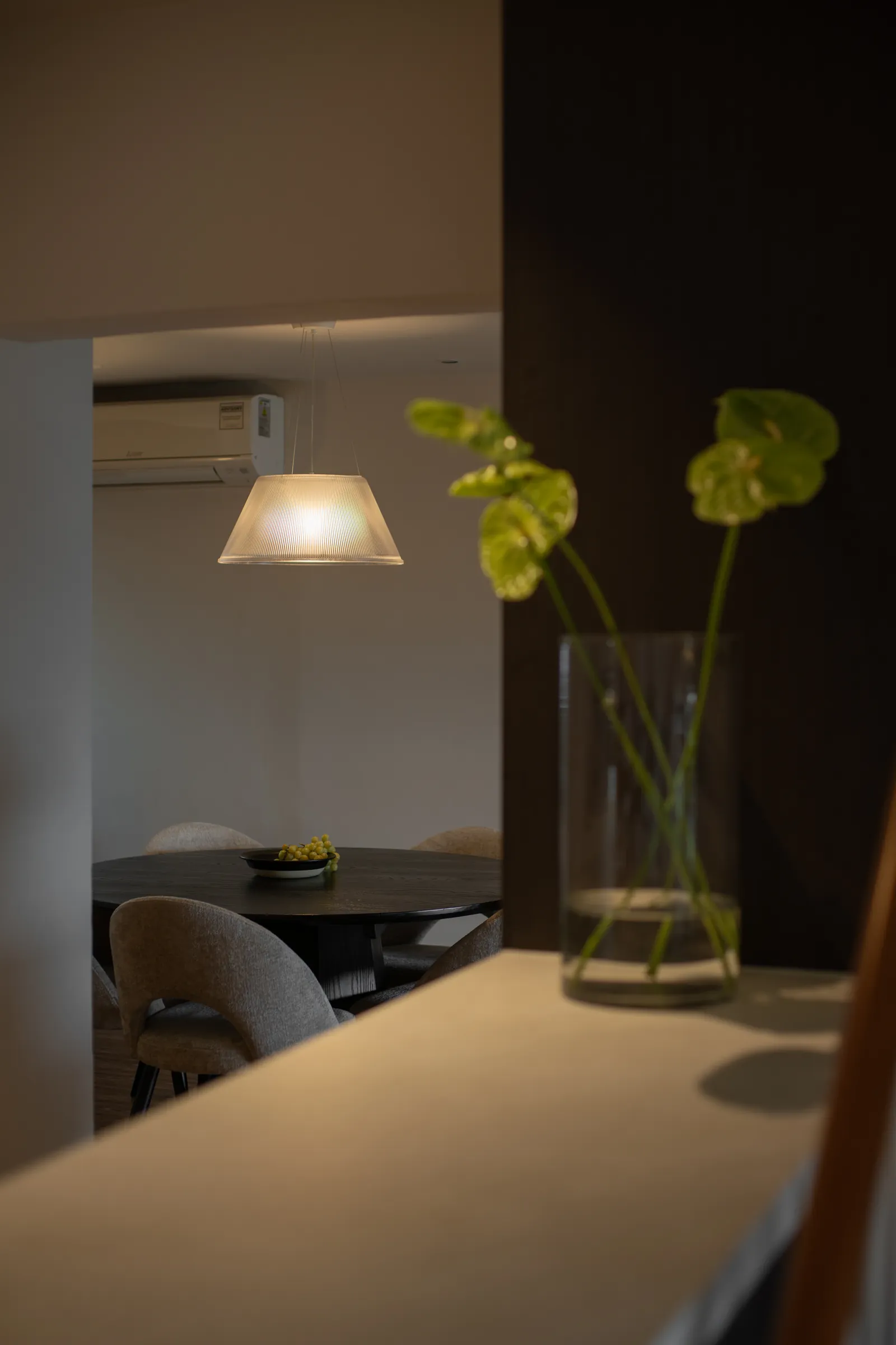 Villa in the Sky: ribbed glass pendant over the dining table, seen past a vase of anthuriums