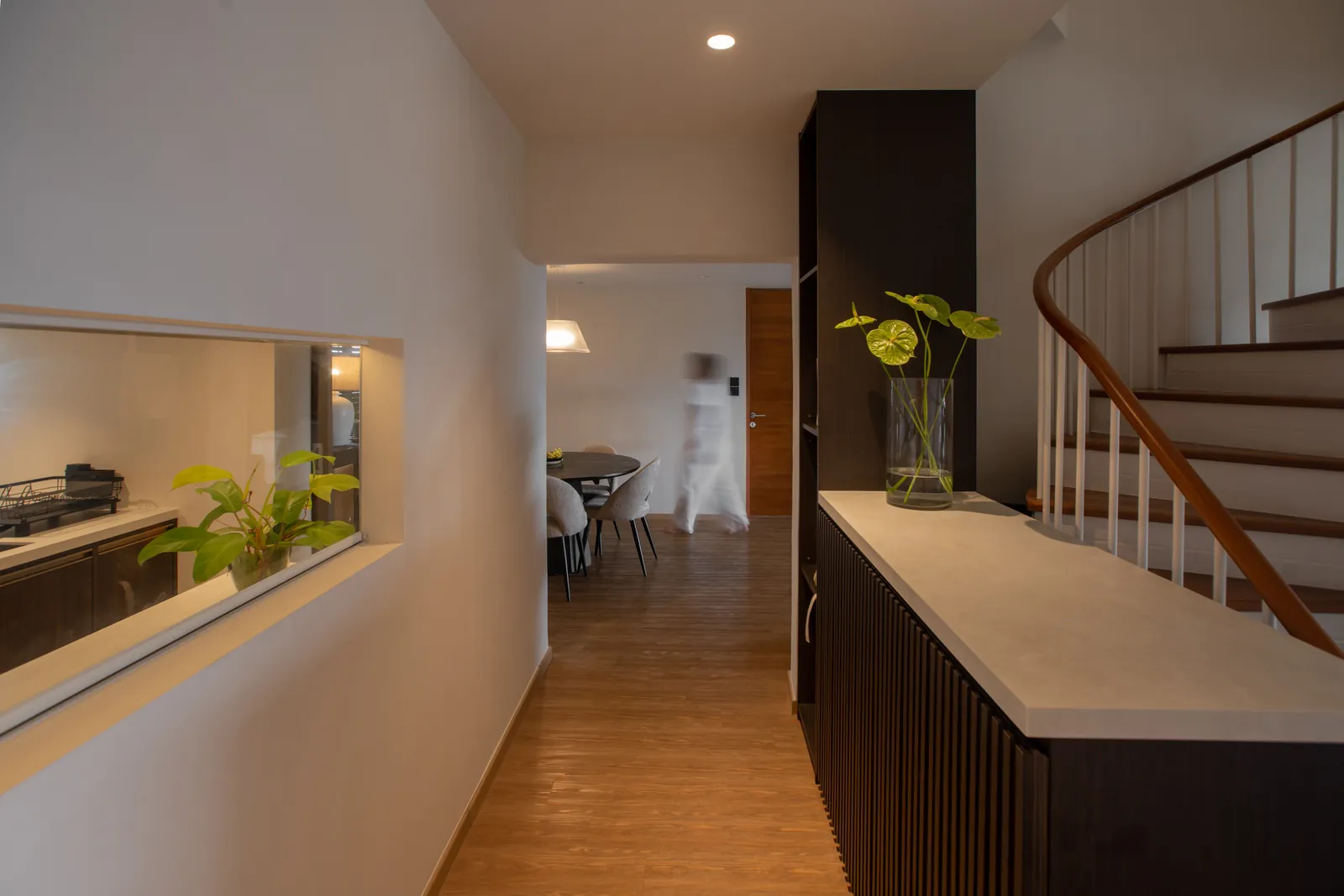 Villa in the Sky: hallway with an internal window to the kitchen and a curved stair