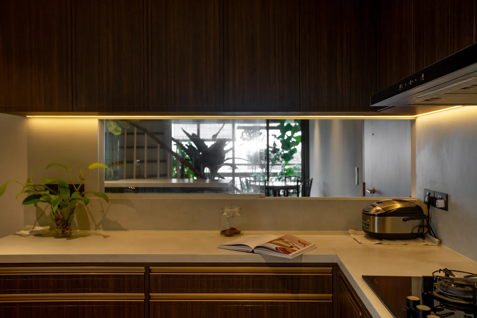 Villa in the Sky: kitchen in dark timber with a pale stone counter and a window strip to the plants