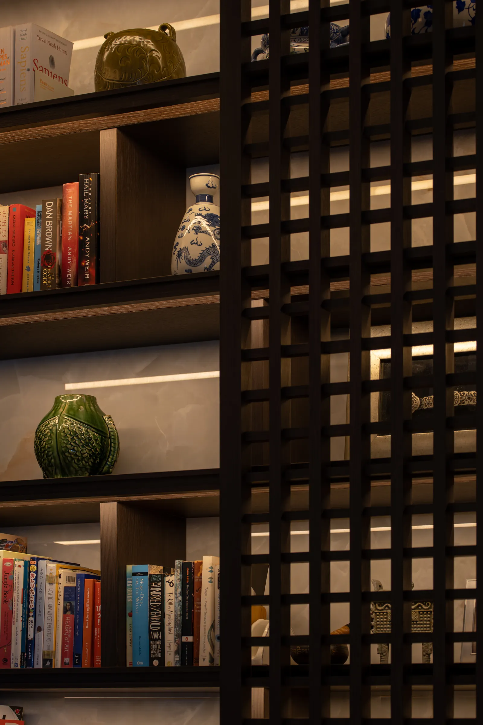 Villa in the Sky: timber lattice screen in front of lit bookshelves and ceramics