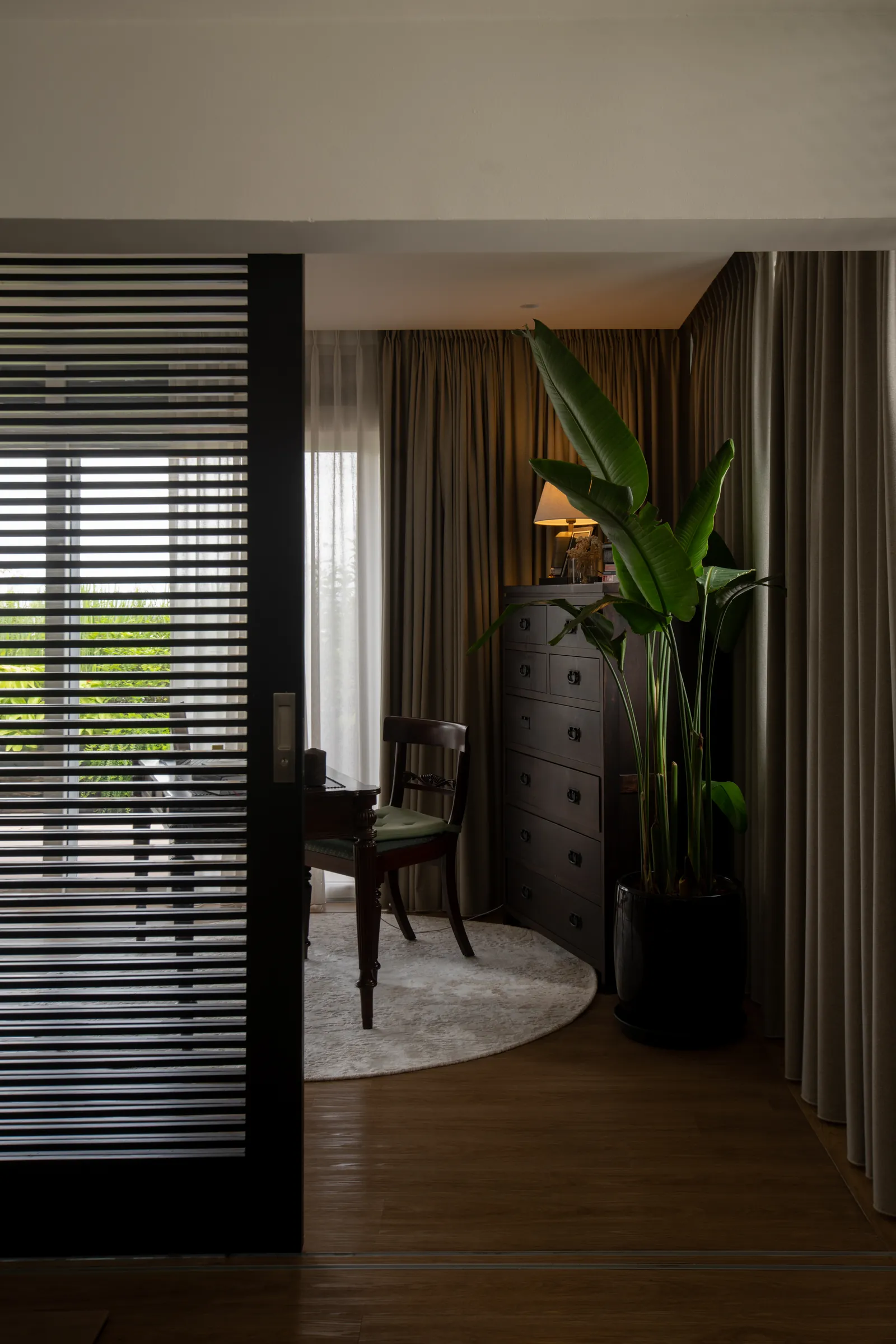 Villa in the Sky: study seen through a louvred screen, with a writing desk and a bird of paradise plant