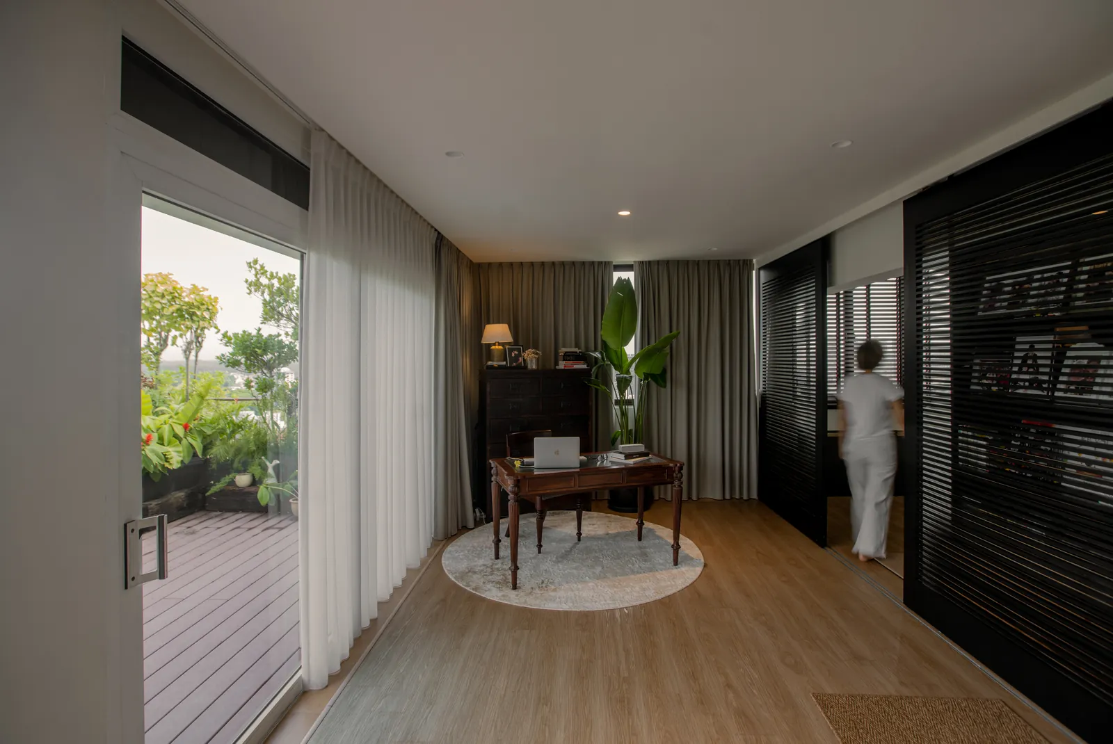 Villa in the Sky: study with a desk on a round rug and glass doors to the planted terrace